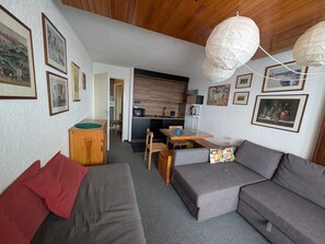 A compact living space with a kitchenette, a dining area, and a seating area with a sofa and a table.