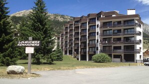 Un edificio a più piani con balconi, un'indicazione per parcheggio privato e montagne sullo sfondo.