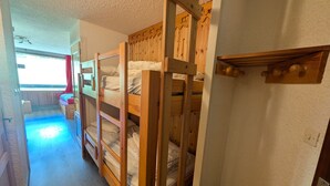 A room with bunk beds, a small seating area, and a window with curtains.