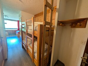 A room with bunk beds, a small seating area, and a window with curtains.