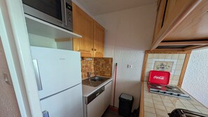 A compact kitchen with a refrigerator, microwave, sink, and stove.