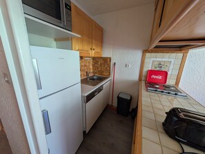 A compact kitchen with a refrigerator, microwave, sink, and stove.