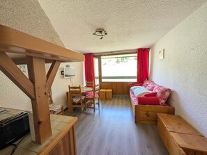 A cozy room with a wooden table, chairs, a sofa, and a television.