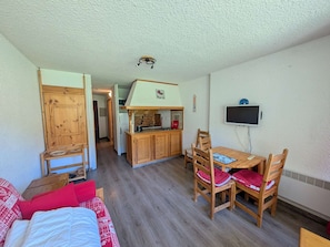 Ein kompakter Wohnbereich mit Küchenzeile, Essbereich und einem Bett.