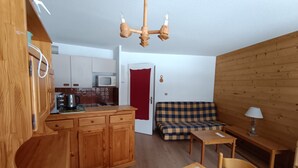 A compact living space with a kitchenette, a sofa, a dining table, and a wooden ceiling. - Spacious apartment on slopes, sleeps 4-6, nice view (Montgenèvre)