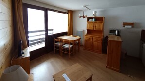 A compact kitchen with wooden cabinets, a dining table, and chairs. - Spacious apartment on slopes, sleeps 4-6, nice view (Montgenèvre)