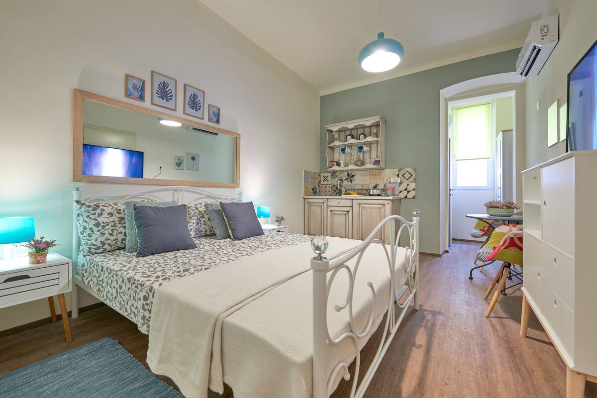 A bedroom with a bed, bedside table, lamp, and a dresser.