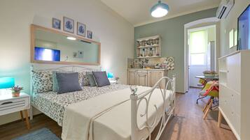 Un dormitorio con cama, mesita de noche, lámpara y cómoda.