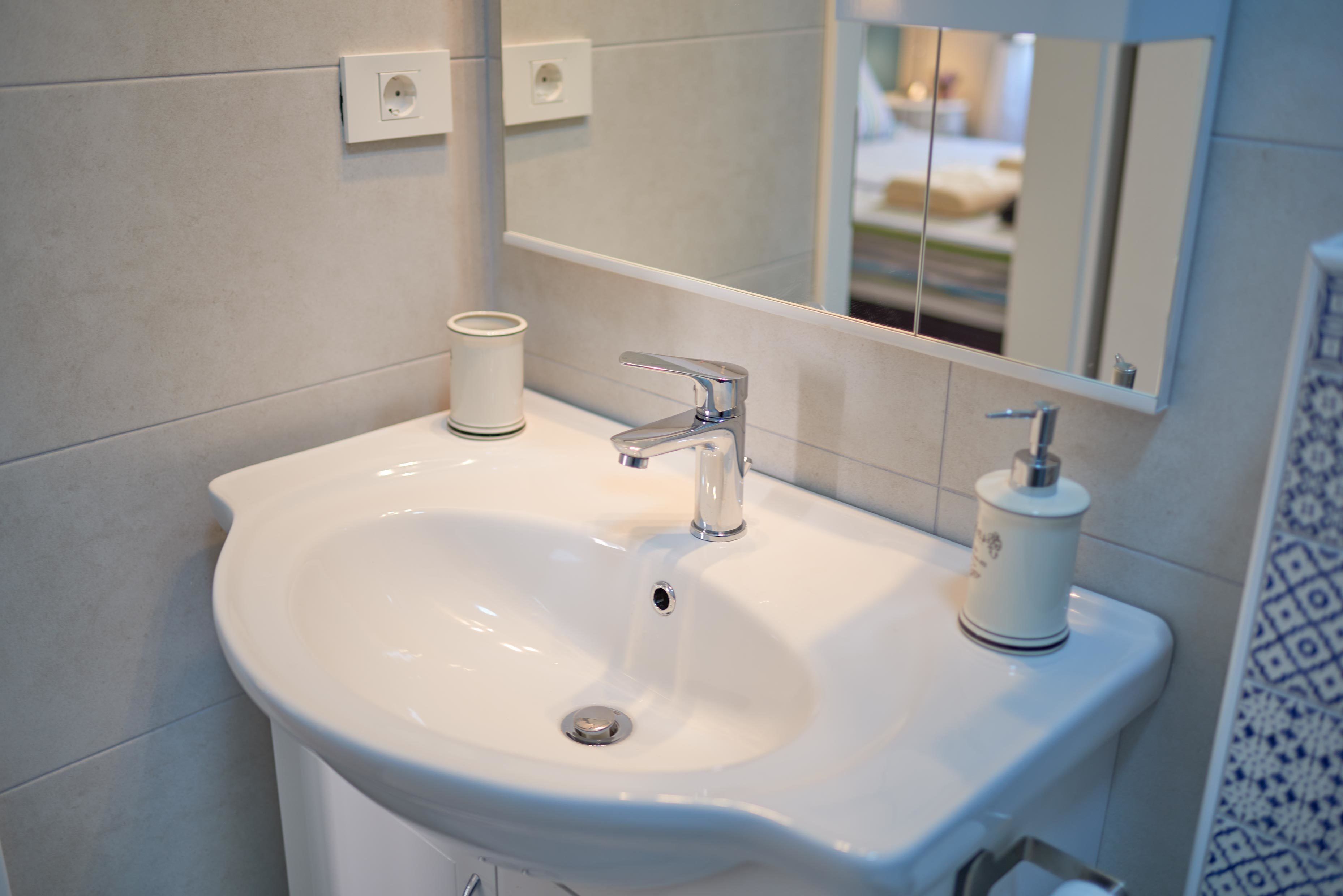 Un baño con lavamanos blanco, un espejo y un inodoro.