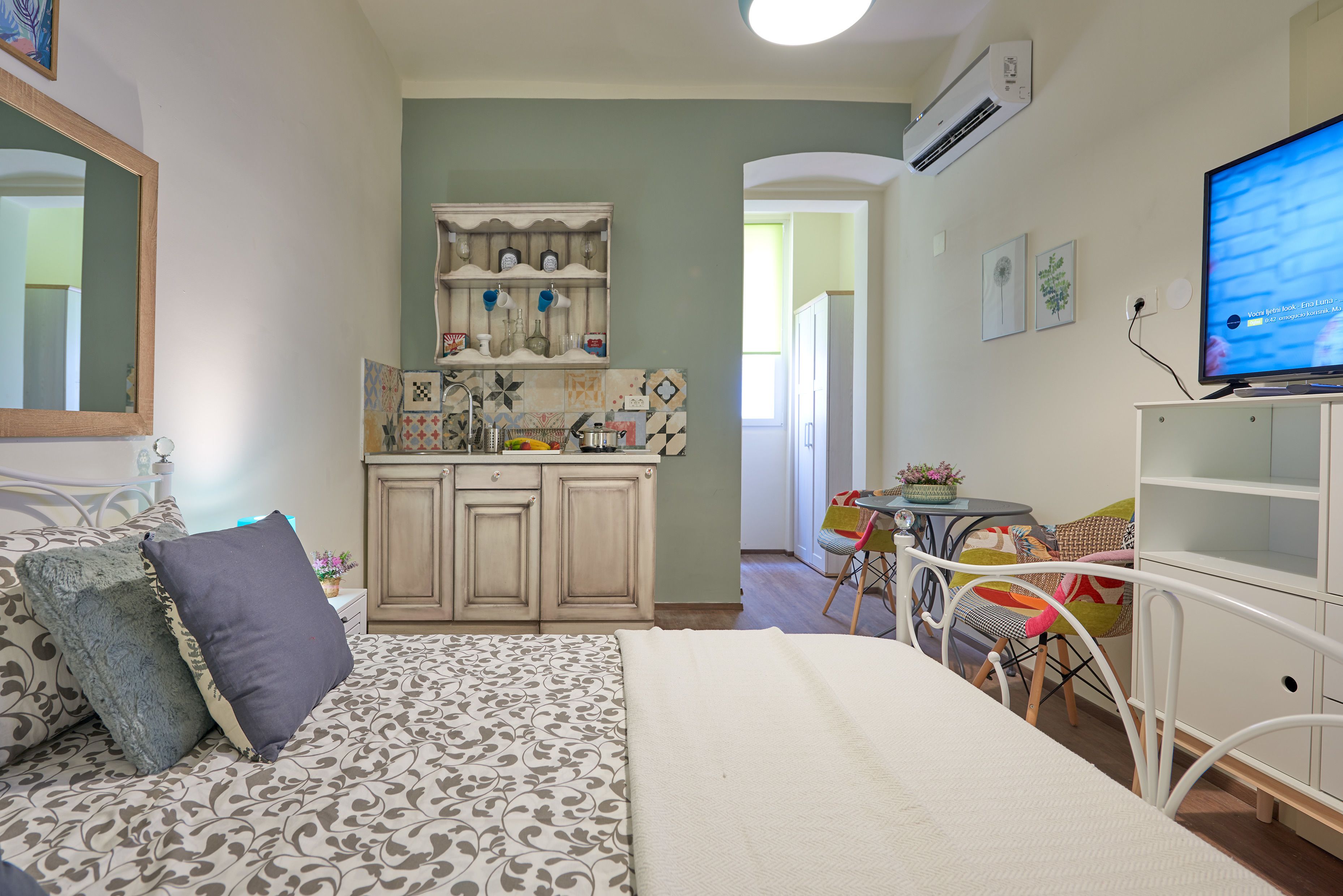Un dormitorio con cama, una kitchenette pequeña, una zona de comedor y televisión.