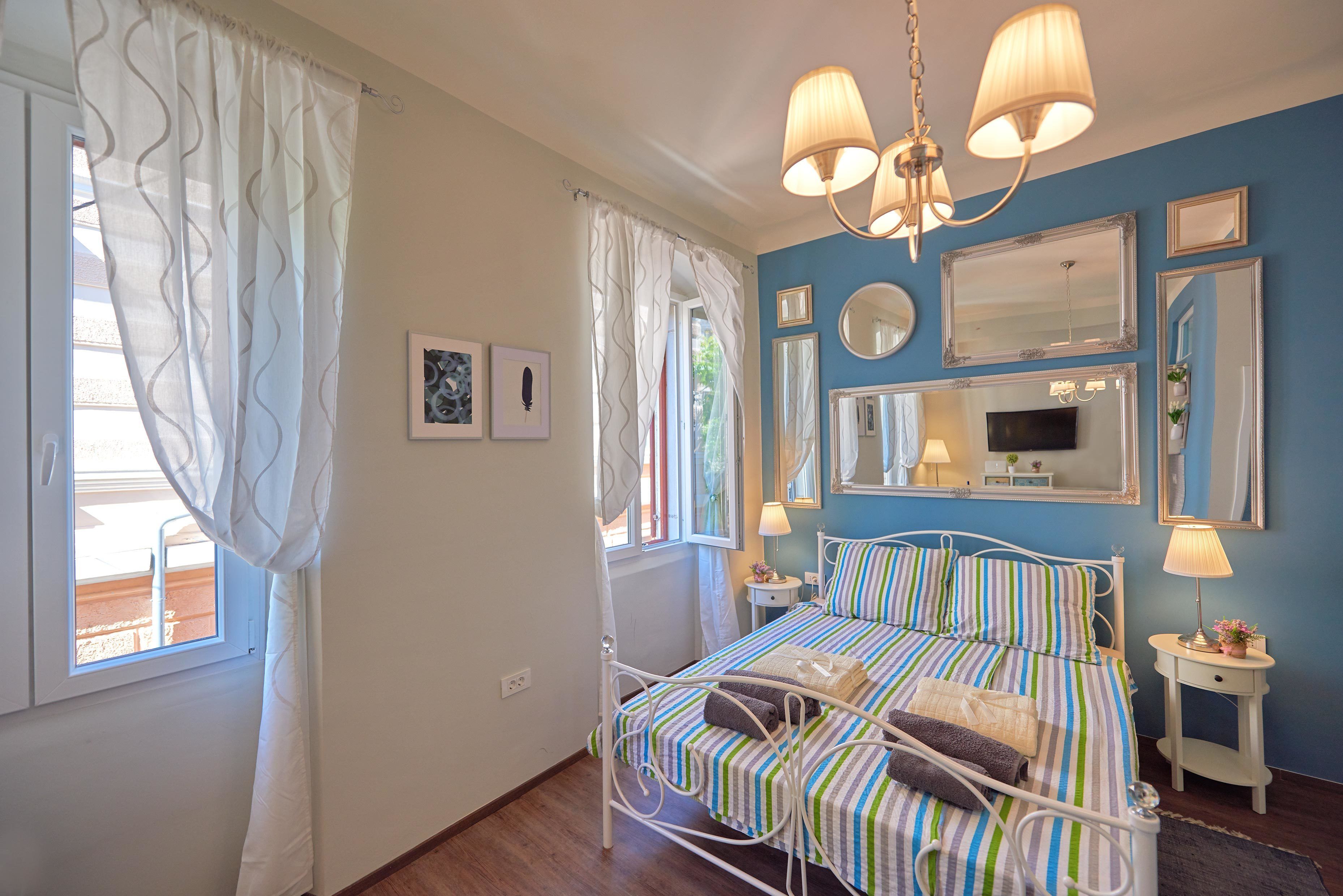 Une chambre à coucher avec un lit, des tables de chevet, un miroir et des rideaux.