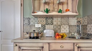 Una cocina con estufa, tostadora, lavabo y un frutero.