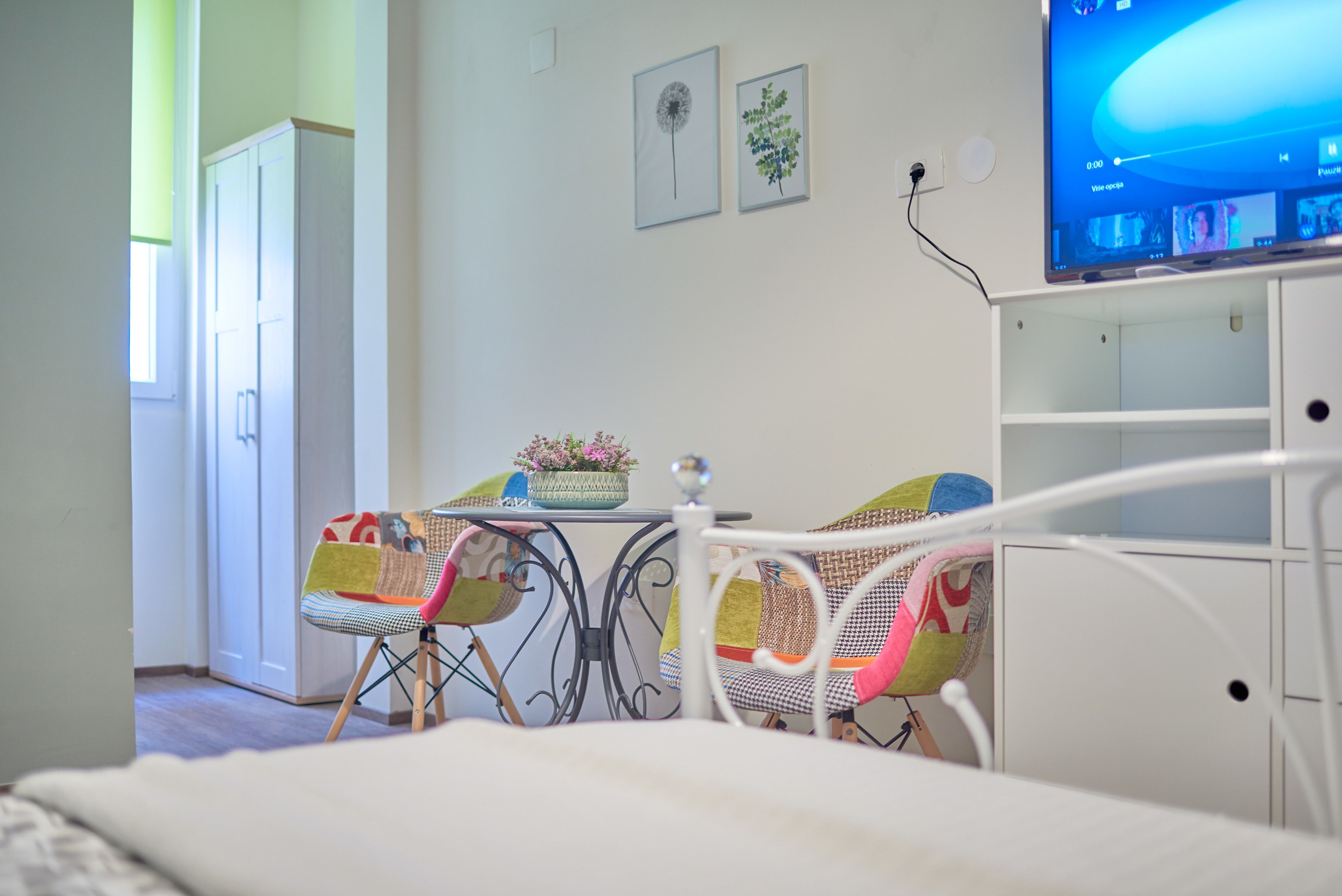 Un dormitorio con cama, una mesita con sillas, televisor y armario.