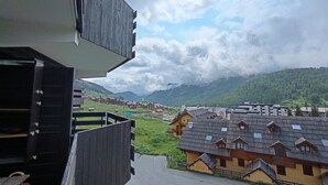 A view of traditional wooden houses with sloped roofs, set against a backdrop of mountains and a cloudy sky. - Spacious apartment for 7 near slopes, pets allowed (Montgenèvre)
