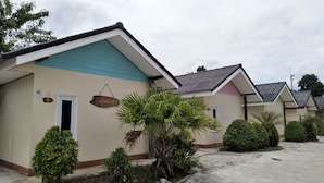 A row of single-story buildings with a uniform architectural style, each featuring a small entrance door, a sign above the door, and a tiled roof. - Kongka Resort (Rayong)