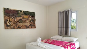 A bedroom with a bed, a painting on the wall, a window with curtains, and a view of greenery outside. - Kongka Resort (Rayong)