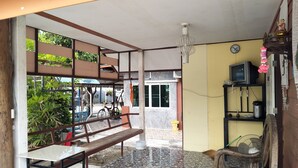 A room with a tiled floor, a bench, a chair, a television, and a clock on the wall. - Kongka Resort (Rayong)