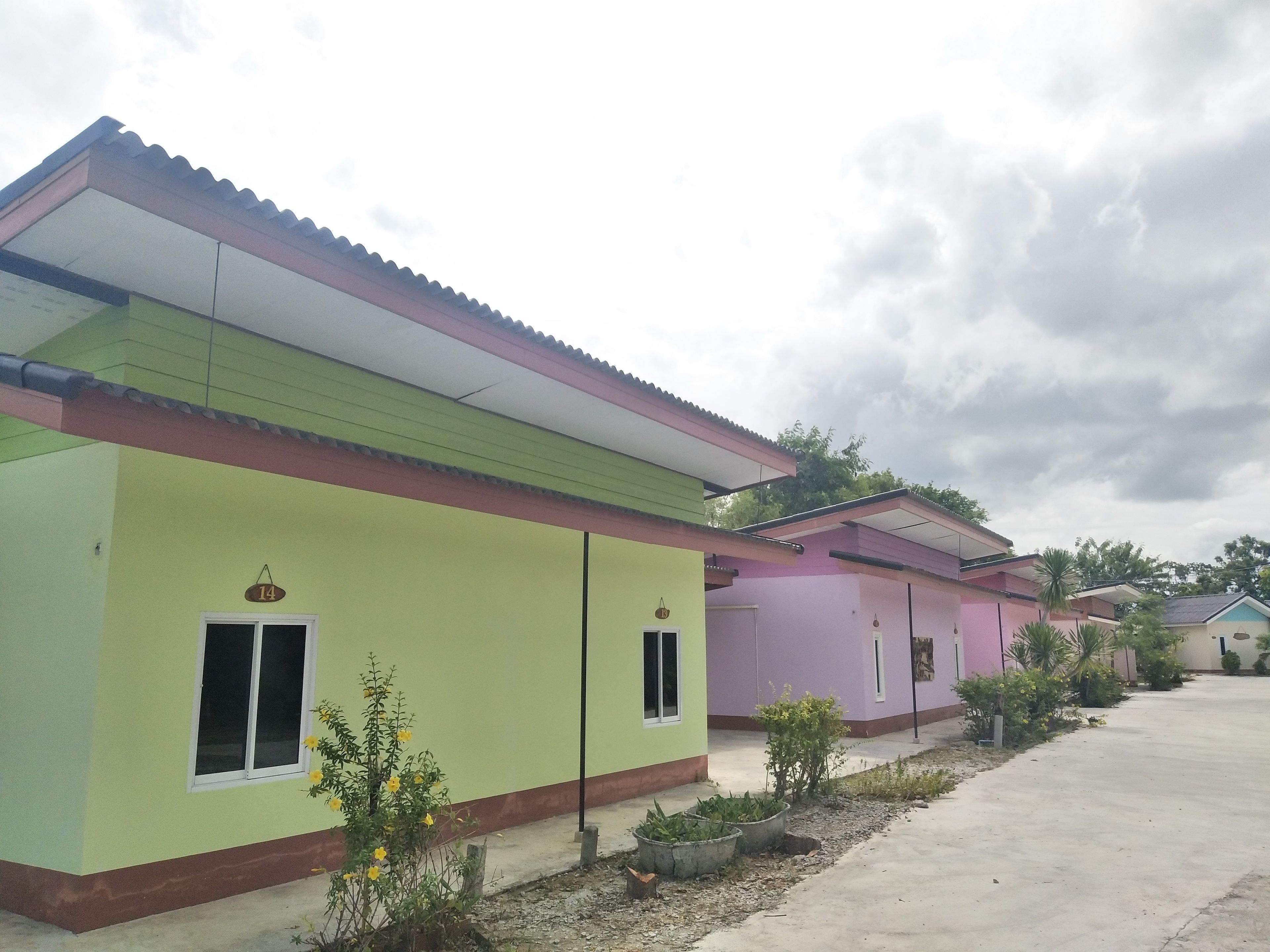 A row of colorful houses with a flat roof, a clear sky, and a concrete pathway.