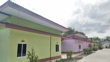A row of colorful houses with a flat roof, a clear sky, and a concrete pathway.