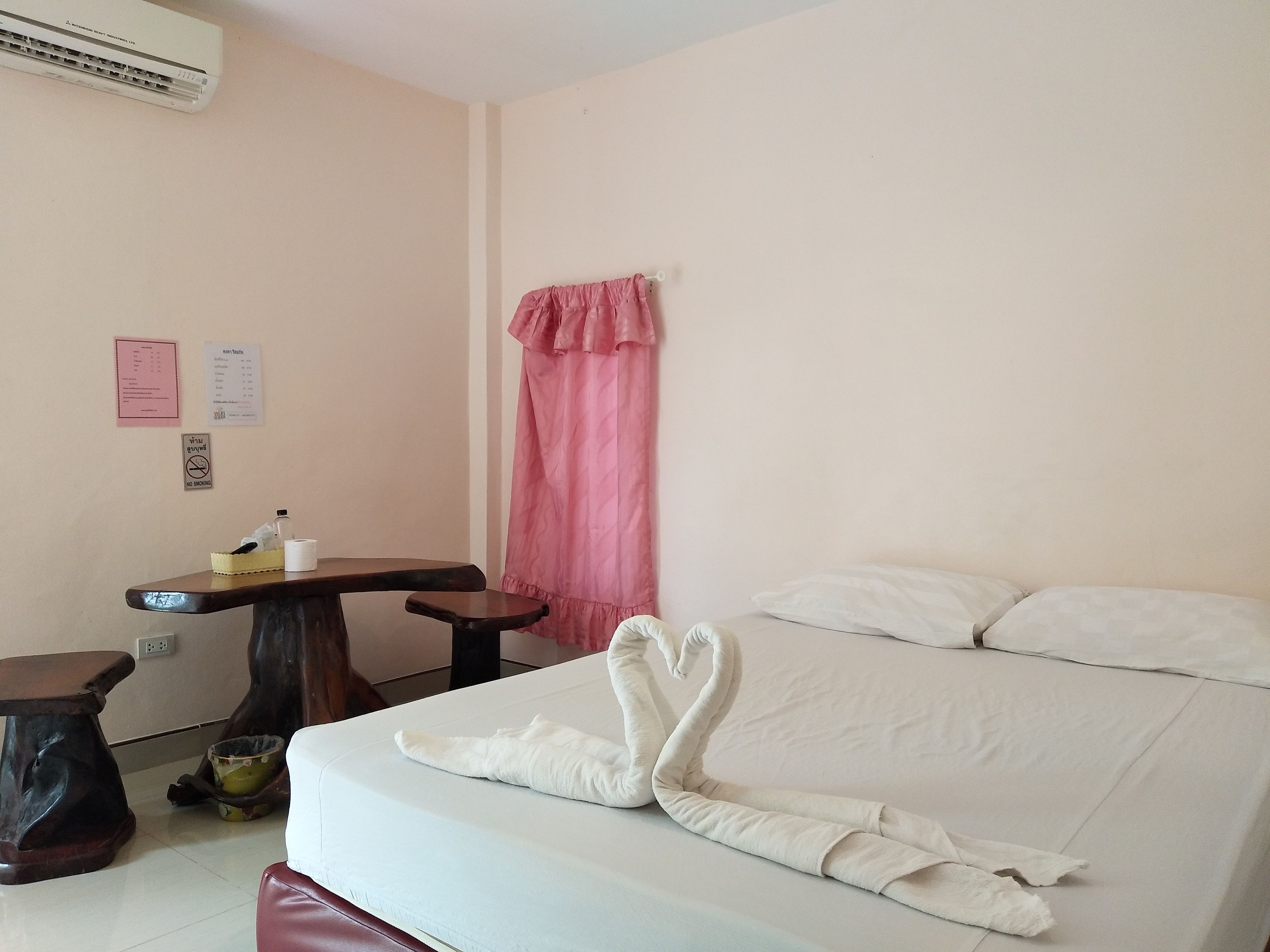 Habitación de hotel con cama, un pequeño escritorio, una silla, una mesa y un aire acondicionado instalado en la pared.