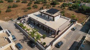 An aerial view of a building with a flat roof, solar panels, and a covered outdoor seating area with tables and chairs. - B&B Il Fiorone (Fasano)