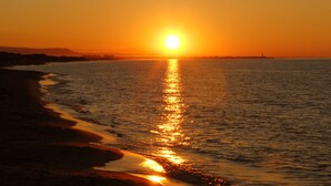 A sunset over a calm sea with a beach on the left. - B&B Il Fiorone (Fasano)