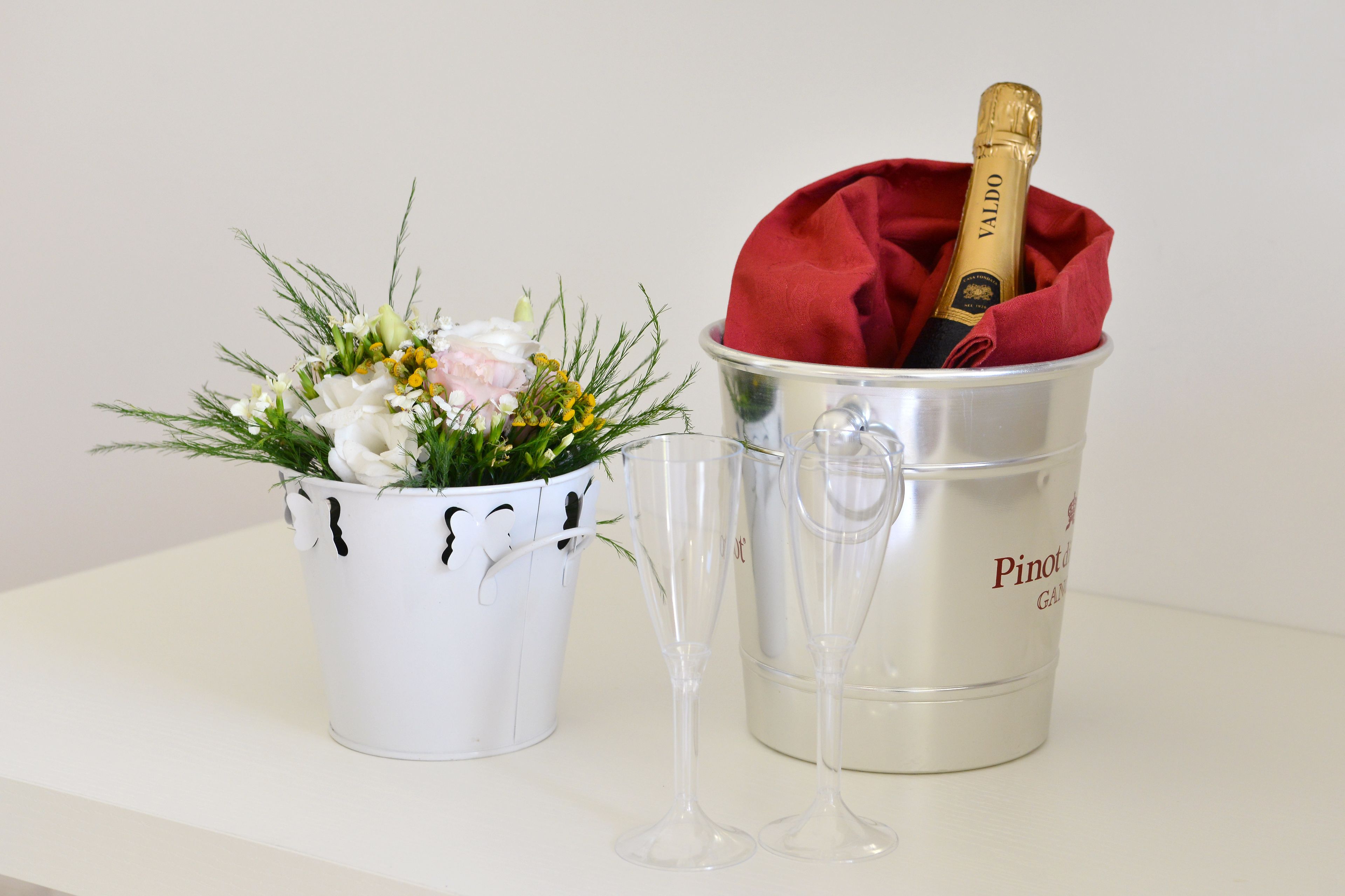 Un cubo blanco con un ramo de flores y una botella de champán.