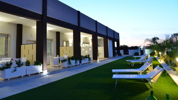 A modern hotel with a covered outdoor area, lounge chairs, and planters. - B&B Il Fiorone (Fasano)