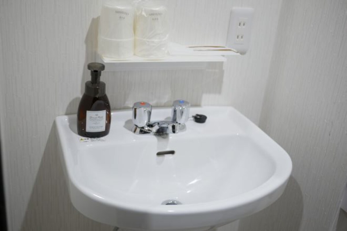 A white bathroom sink with a bottle of hand soap and a soap dispenser.