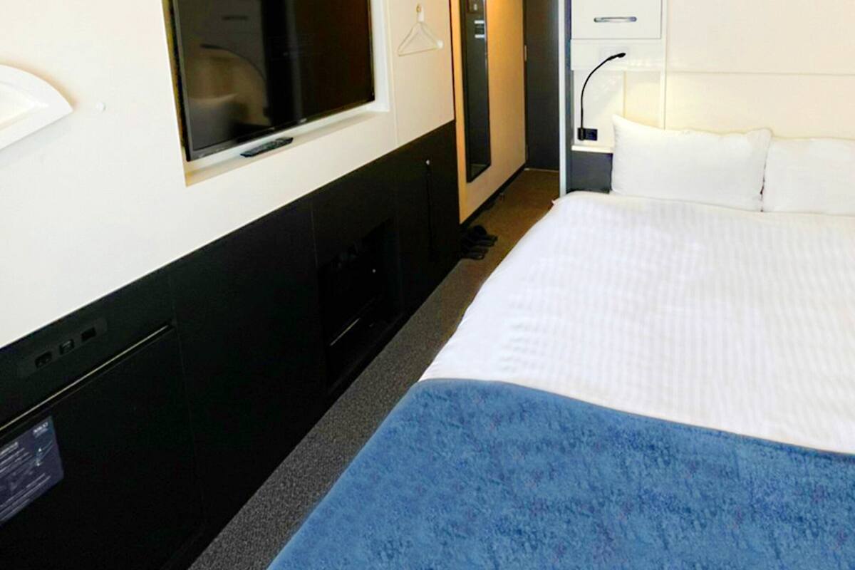 A hotel room with a bed, a TV, a wardrobe, and a bedside table.