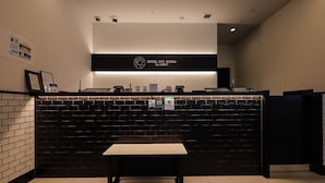 A reception area with a black counter, a bench, and a sign indicating free Wi-Fi. - HOTEL SUI KANDA byABEST (Tokyo)