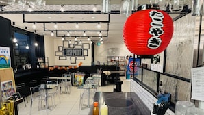 Un interior de restaurante moderno con mesas de vidrio transparente, un farol rojo y una variedad de platos en exhibición.
