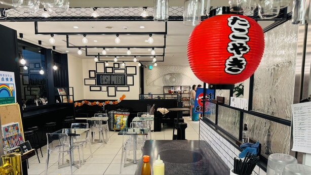 Un interior de restaurante moderno con mesas de vidrio transparente, un farol rojo y una variedad de platos en exhibición.