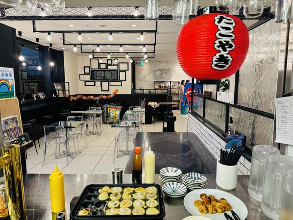 A modern restaurant interior with clear glass tables, a red lantern, and a variety of dishes on display. - HOTEL SUI KANDA byABEST (Tokyo)