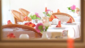 A dining table set with chairs, a vase with flowers, and a candle. - Hotel Reinhardtshof Garni (Wolfschlugen)
