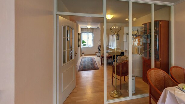 Um corredor amplo com área de jantar, uma porta de vidro que dá para um quarto e um armário de madeira.