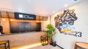 A hotel reception area with a wooden counter, a reception desk, and a wall with a decorative metal design and text indicating the hotel's location in Tokyo, Asakusa, and room number 23. - ICI HOTEL Asakusabashi (Tokyo)