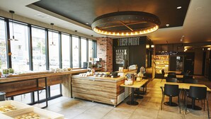 A modern cafe with a wooden counter, seating area, and large windows. - ICI HOTEL Asakusabashi (Tokyo)