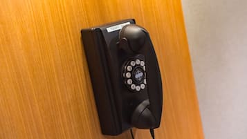 Um telefone preto fixado em uma superfície de madeira.
