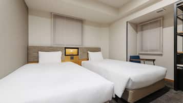 Habitación de hotel con dos camas individuales, un escritorio y una silla.