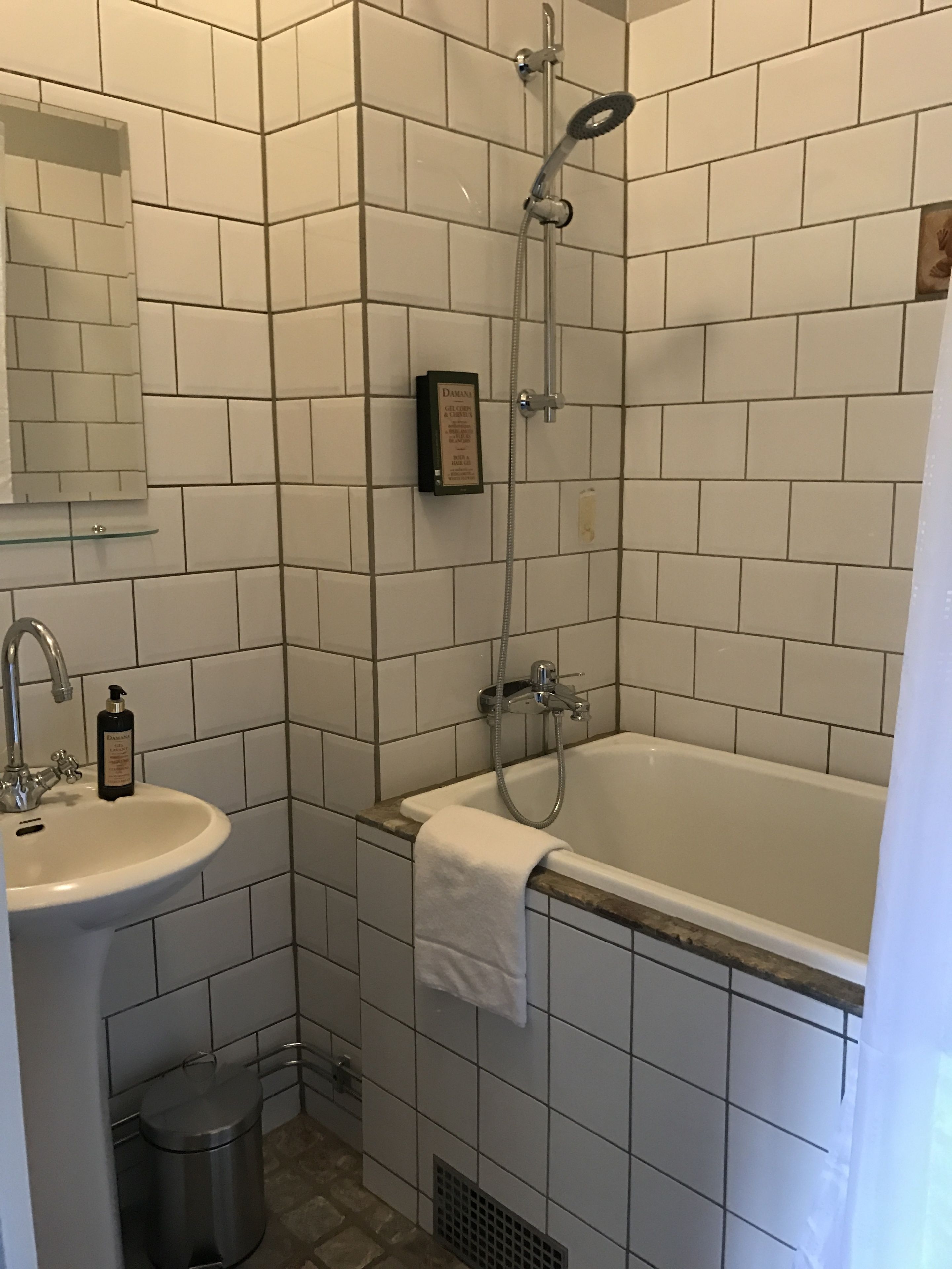 Un bagno con un lavandino bianco, una vasca e una doccia. Sopra il lavandino c'è uno specchio e, sulla parete, una targa incorniciata.