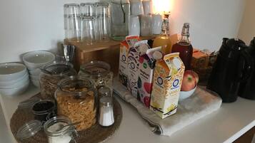 En köksbänk med olika livsmedel, inklusive burkar med kryddor, en skål med flingor och förpackningar med mjölk och yoghurt.