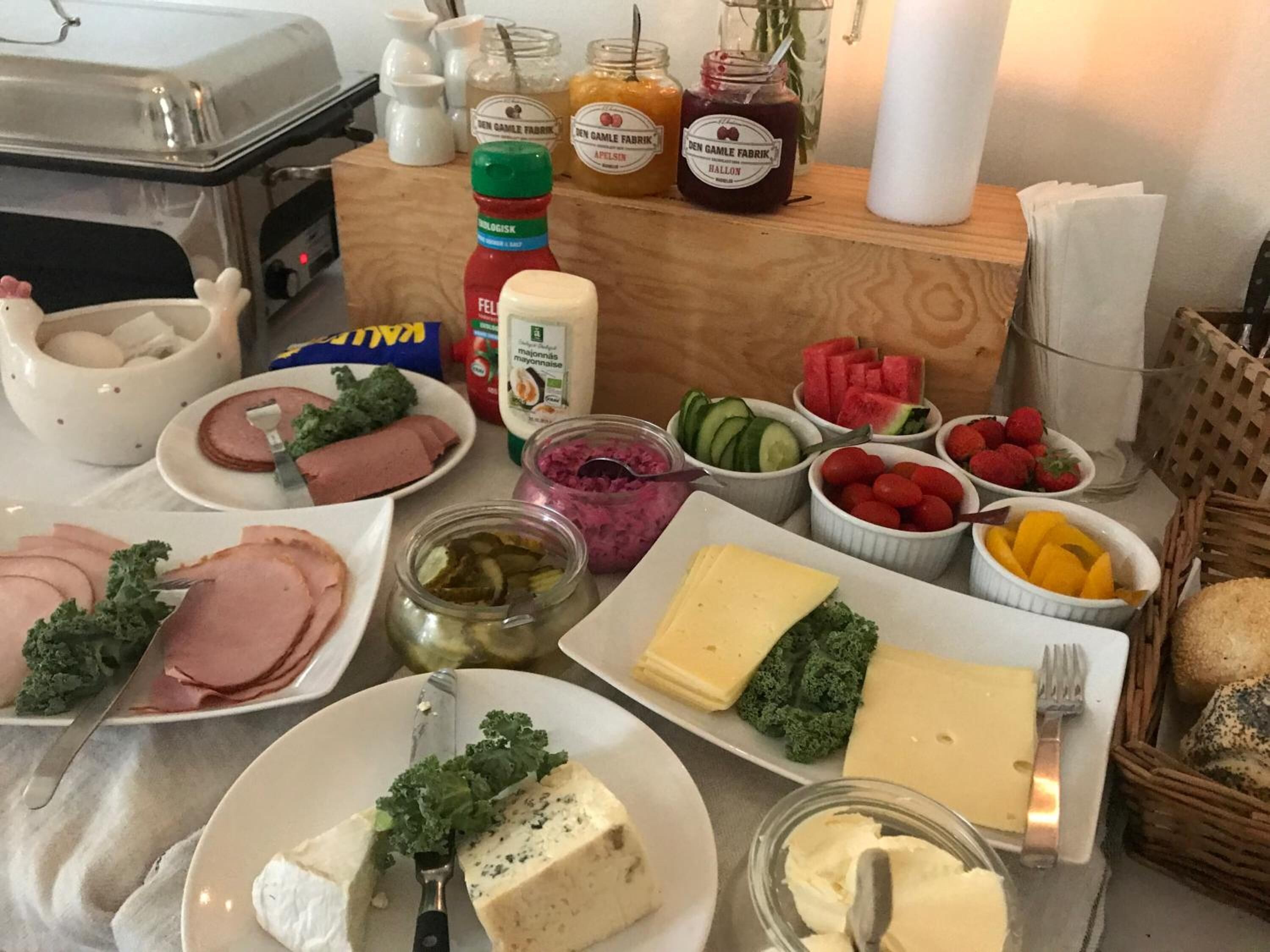 A buffet table with various food items including meats, cheeses, fruits, and condiments.