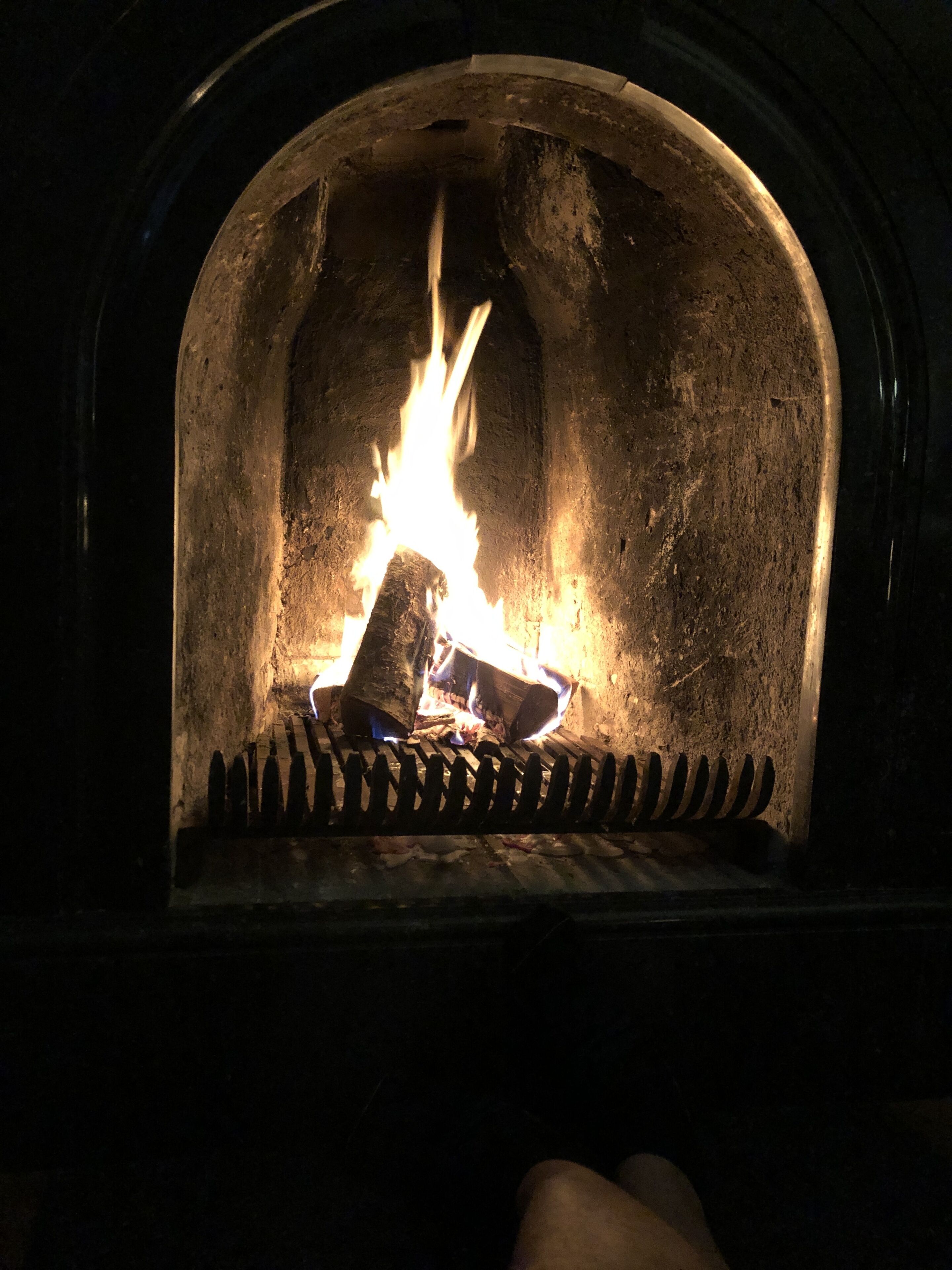 Una chimenea con fuego encendido, rodeada de una pared de piedra.