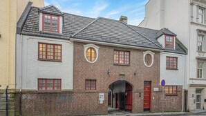 Een klassiek bakstenen gebouw met een rode deur, meerdere ramen en een pannendak.