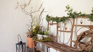 A rustic bench with a metal frame, adorned with greenery and small potted plants. - Ferienwohnung Kaiserfeld (Reit im Winkl)