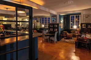 Un hall d’hôtel accueillant, dot é d’un bar, de plusieurs coins salon et offrant une vue sur la ville grâce à de grandes fenêtres.