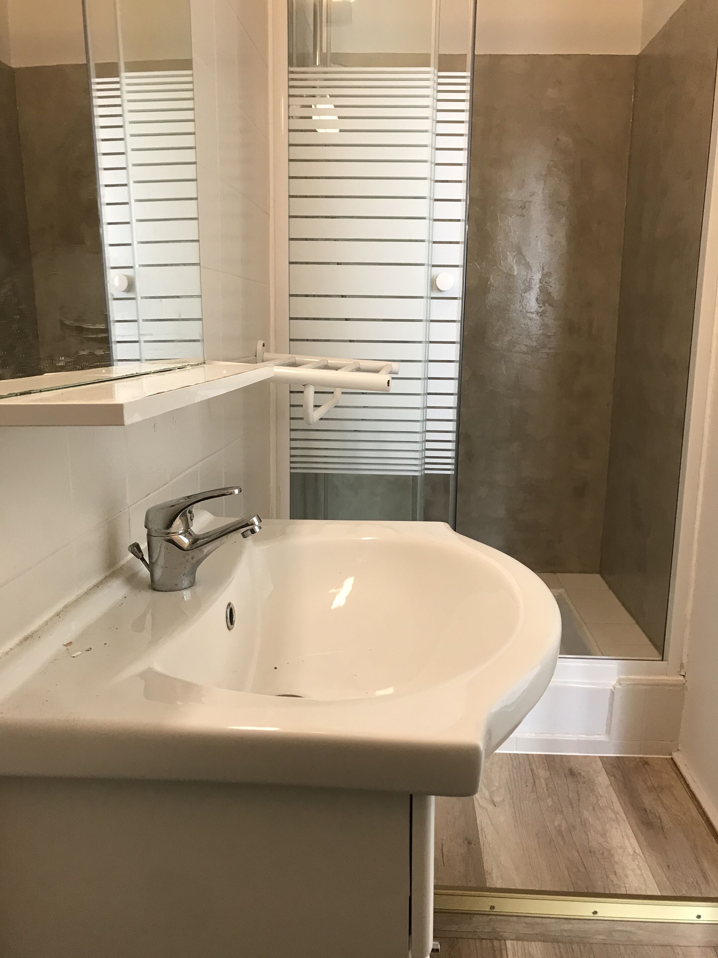 A bathroom with a white sink, a mirror, and a shower area.
