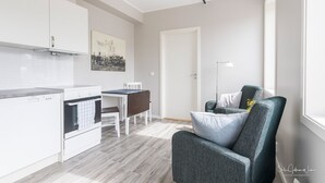Een moderne keuken met witte kasten, een eettafel met stoelen en een grijze fauteuil.