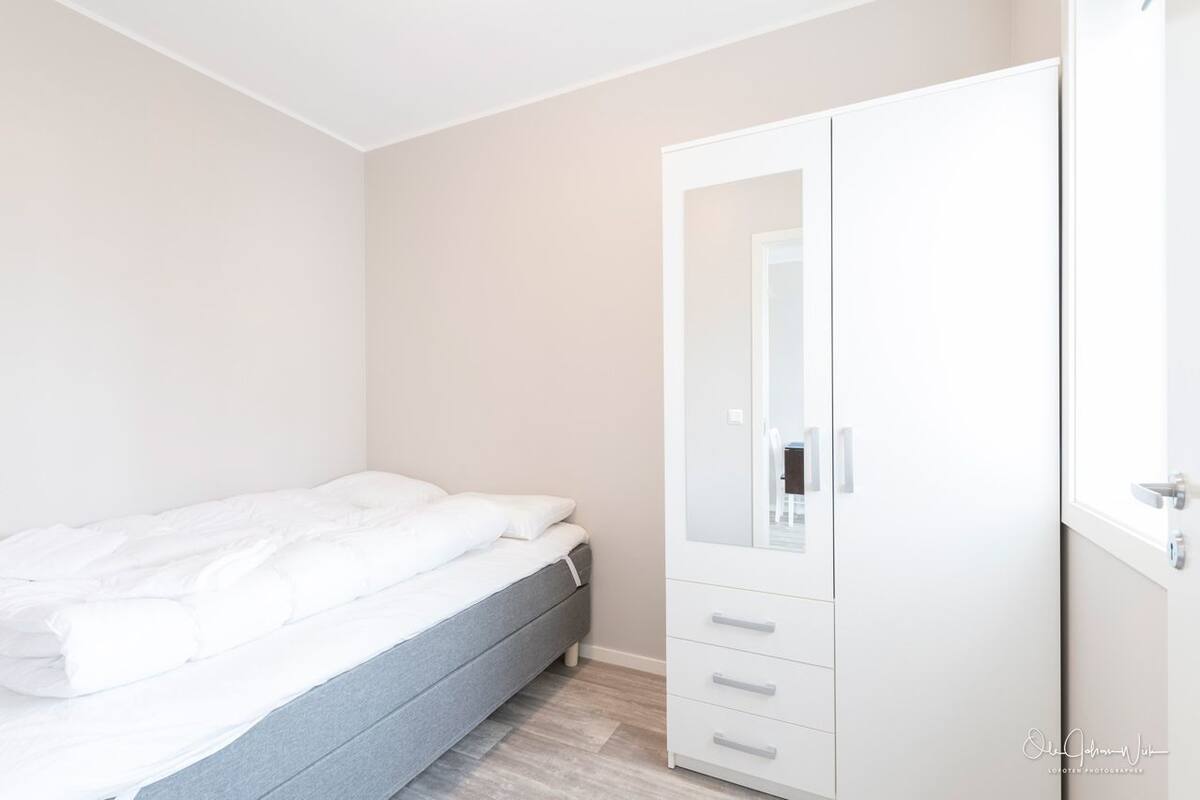 Een slaapkamer met een bed, een kledingkast en een spiegel.